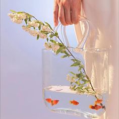 a person holding a vase filled with water and goldfish