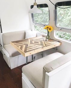 a table with flowers on it in front of two couches and a small window