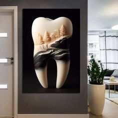 a tooth shaped artwork hanging on the side of a wall next to a potted plant