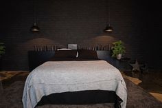 a bed with two lamps on either side of it and a black brick wall in the background