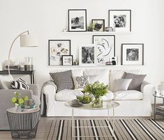 a living room filled with white furniture and pictures on the wall above it's coffee table