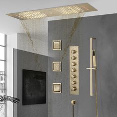 a modern bathroom with grey walls and gold fixtures on the shower head, hand held by a brass faucet