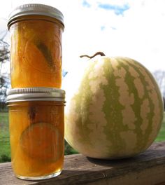 two jars filled with liquid next to a watermelon