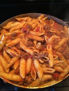 a skillet filled with pasta and sauce on top of an oven burner stove