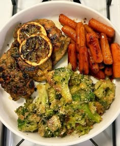 a white plate topped with meat, broccoli and carrots next to other foods