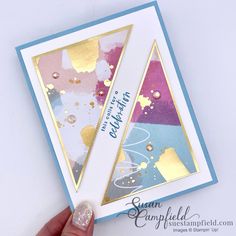 a hand holding up a card with gold foil on it and some confetti