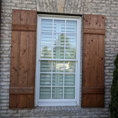 an open window with wooden shutters in front of a brick building