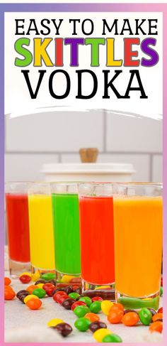 three glasses filled with different colored drinks on top of a white table next to candy