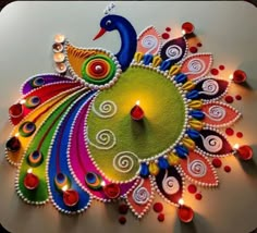 a colorful peacock made out of candles on top of a white surface with red, green, and blue lights