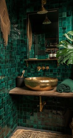 a bathroom with green tiles and a gold sink in the middle, surrounded by plants