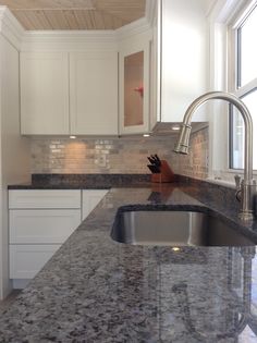 an image of a kitchen with granite counter tops and stainless steel sink faucet