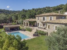 an aerial view of a house with a pool in the foreground and trees surrounding it