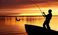 a man standing on top of a boat while holding a fishing rod in his hand