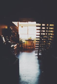 the sun shines through an open door into a dark room with stairs leading up to a table