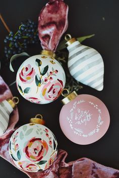 christmas ornaments are sitting on the table with pink and white decorations around them, including one ornament