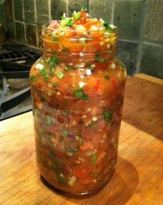 a jar filled with lots of food sitting on top of a wooden table next to a stove