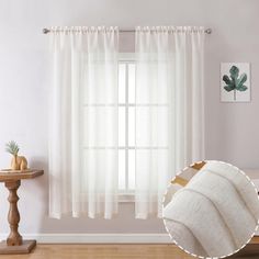 a white curtain hanging on the side of a wall next to a table with a potted plant