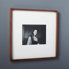 a black and white photo hanging on the wall next to a wooden frame with a woman's face