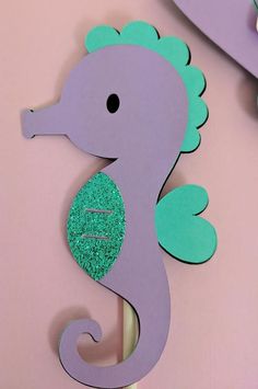 a purple and green sea horse on a pink wall next to two other wooden signs