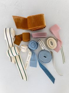 several different types of ties laid out on a white surface with one being rolled up