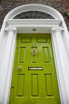 a green front door with white trim on an old brick building