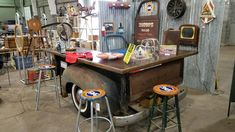 an old truck is parked in a garage with several stools on the floor and various items around it