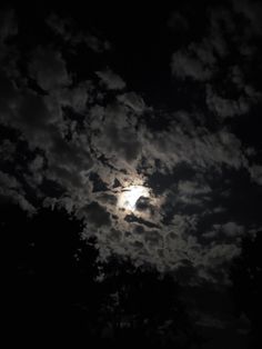 the moon is shining brightly in the dark night sky with clouds and trees around it