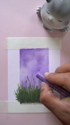 a person is drawing grass on the wall with a purple pencil and watercolor paper