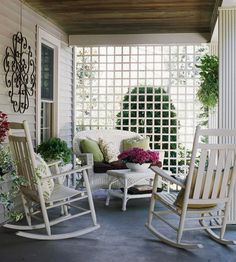 a porch with rocking chairs and potted plants on the front porch, next to a pergolated screen door