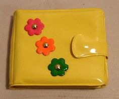 a yellow purse with flowers on it and a button in the middle, sitting on a table