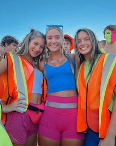 three girls in neon vests and shorts posing for the camera with their arms around each other