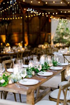 the tables are set with white plates and greenery on them, along with candles