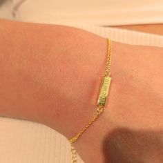 a woman's arm with a gold bracelet that has a name tag on it