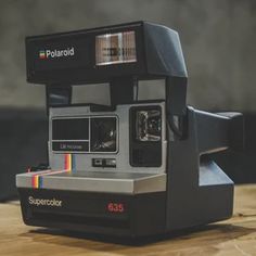 an old polaroid camera sitting on top of a wooden table