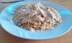 a blue plate topped with rice and meat covered in gravy on top of a wooden table