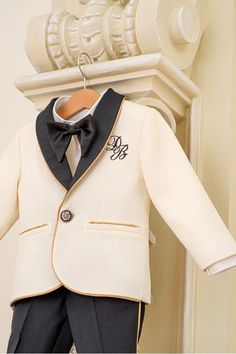 A classic combination of ivory and black with golden details. the jacket is embroidered with the little ones initials. A perfect suit for the Holidays season, a wedding or a baptism! Please measure the little one prior to ordering, to be sure the suit fits him. The measurements that you need to take are. Height Chest Circumference Waist Circumference Hips Circumference Color: black and ivory. Suit components: suit jacket, trousers and shirt with bowtie. Composition: wool, cotton, rayon, viscose Classic Gold Formal Sets, Classic Gold Sets For Formal Occasions, Cream Long Sleeve Tuxedo For Formal Occasions, Gold Tuxedo Suit For Groom, Classic Gold Wedding Sets, Classic Cream Blazer For Party, Classic Gold Blazer With Suit Collar, Gold Classic Formal Blazer, Elegant Gold Suits For Ceremony