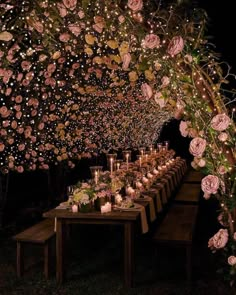 a long table with candles and flowers on it is lit up in the night sky