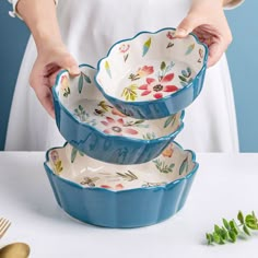 the woman is holding three dishes in her hands and placing them into each other's bowls