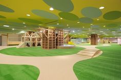 an indoor play area with green grass and wooden structures on the ceiling, painted in bright colors