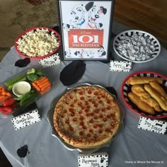 a table topped with pizza and other food items next to a sign that says 101 dalmatian