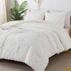 a bed with white comforter and pillows in a room