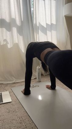 a woman is doing yoga in front of a laptop