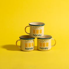 three coffee mugs with the words honey on them sitting in front of a yellow background