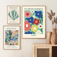 three flower market posters hanging on the wall above a table with vases and flowers