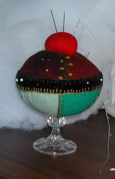 a close up of a glass cup on a table with snow behind it and a red ball in the middle