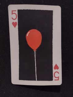 a playing card with a red balloon on the front and black back, which reads 50