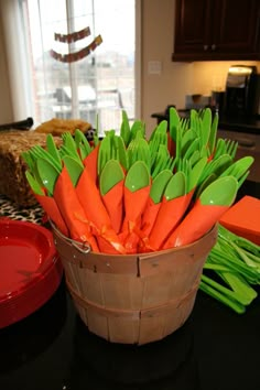 a basket filled with carrots sitting on top of a counter next to a red bowl