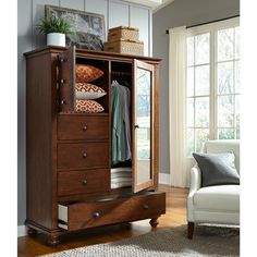 a wooden armoire with drawers and clothes on it