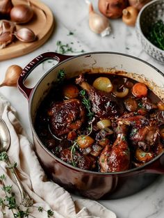 a pot filled with meat and vegetables on top of a table next to other dishes