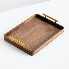 a wooden tray with two gold handles on the top and bottom, sitting on a white surface